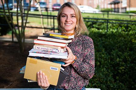 A student holding a stack of textbooks ready for her classes at JSU